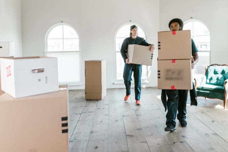 Twee verhuizers dragen dozen een lege woning in