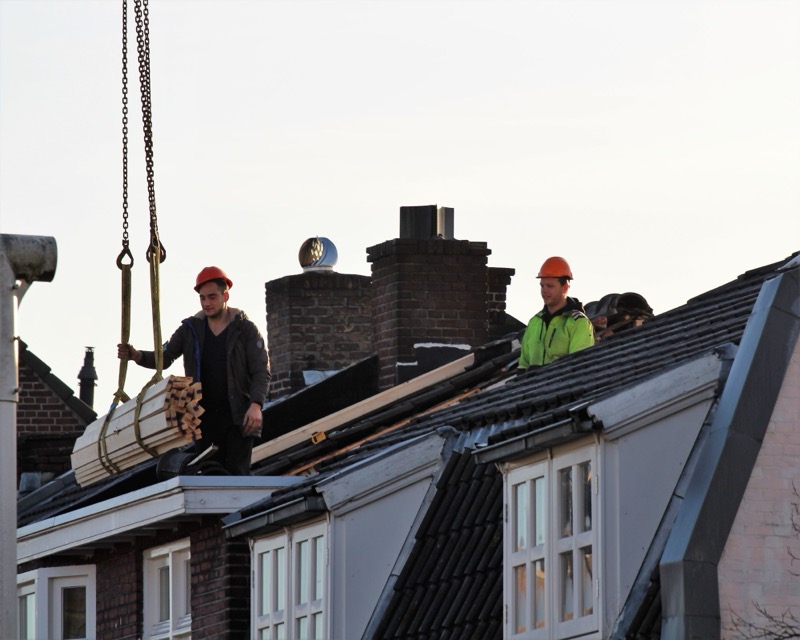 Twee bouwvakkers op het dak van een rijhuis tijdens een renovatie