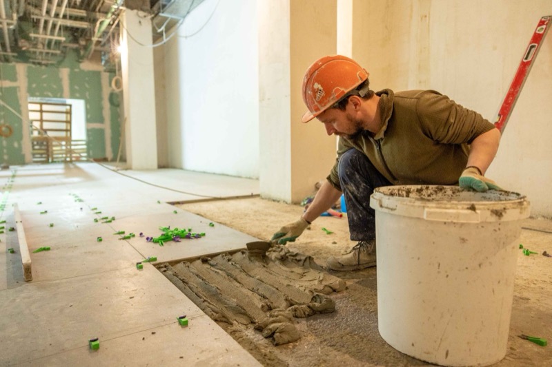 Vakman brengt lijm aan op een vloer tijdens een renovatie